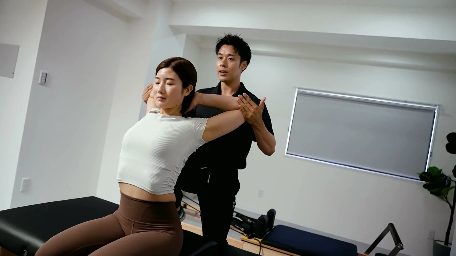 男性トレーナーが座った利用者の肩と胸をストレッチする様子